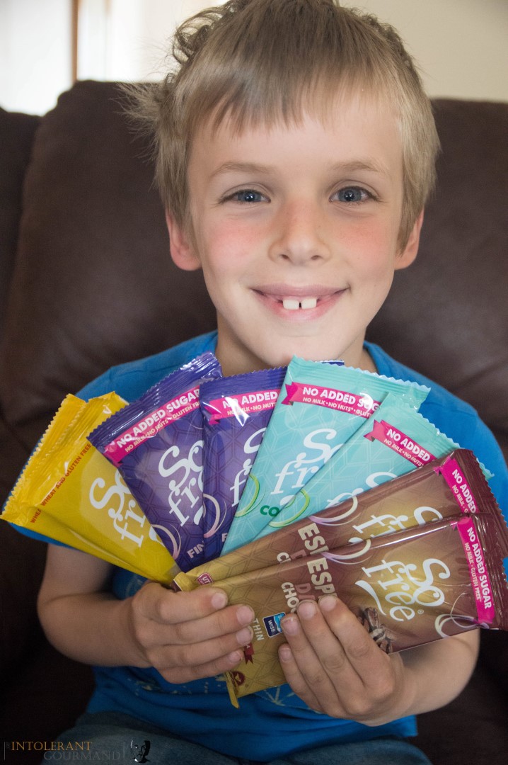 Callum holding a selection of chocolate bars with a big smile on his face! dairy-free and gluten-free chocolate bars that are also vegan! www.intolerantgourmand.com